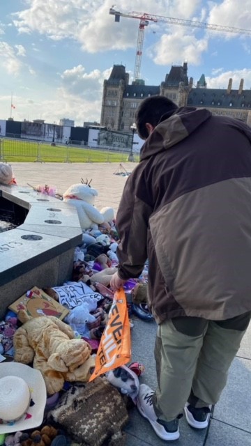 Nation Harrington places an Every Child Matters flag near the eternal flame on Parliament Hill in Ottawa